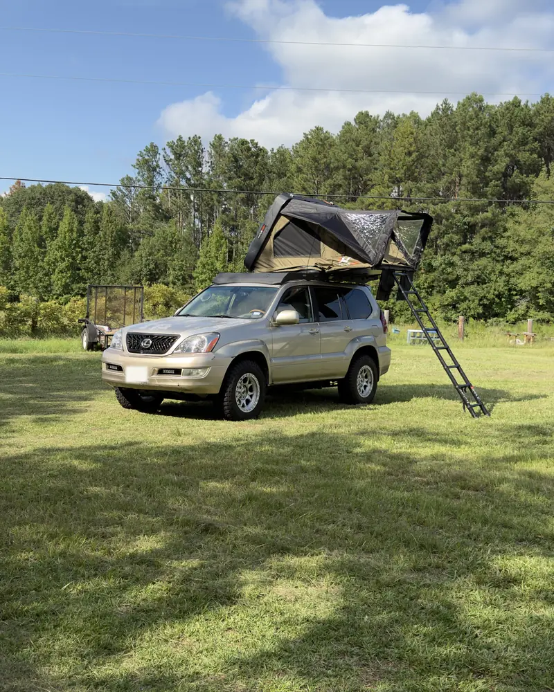 Ginny camped in a grassy field, tent and ladder out